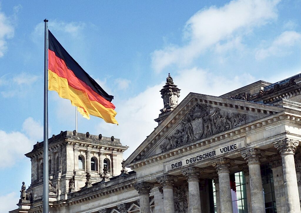 white concrete building with flags on top under blue sky during daytime