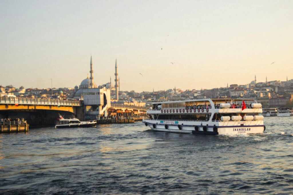 A ferry cruises near the iconic Galata Bridge in Istanbul, with mosques in the background.