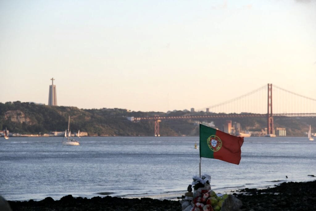 a flag on a beach with a bridge in the background