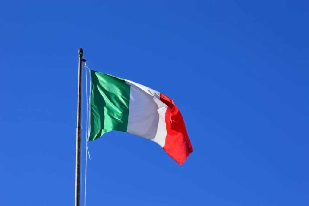 Italian flag flying against a vibrant blue sky, symbolizing national pride and identity.