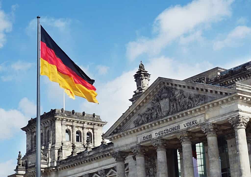 white concrete building with flags on top under blue sky during daytime