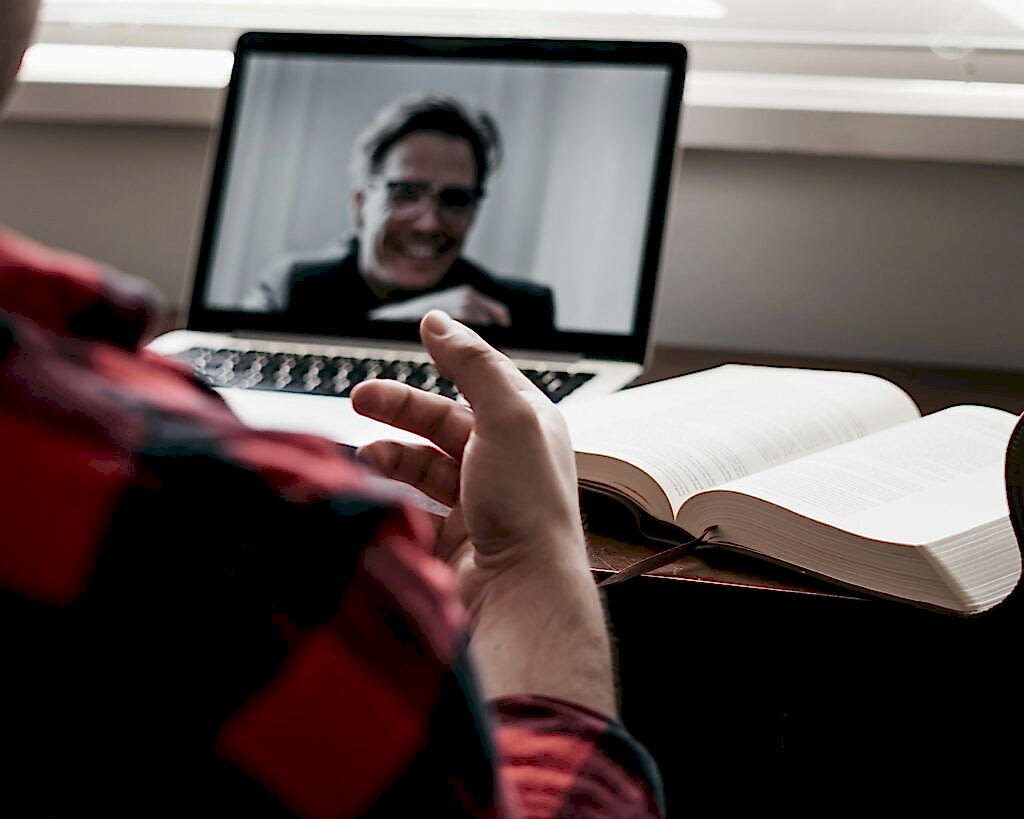 person in red and black plaid long sleeve shirt using black laptop computer