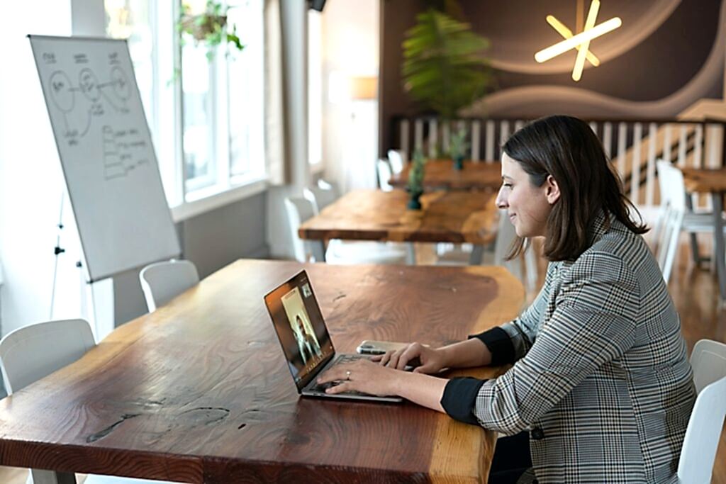 woman in gray and white striped long sleeve shirt using silver macbook